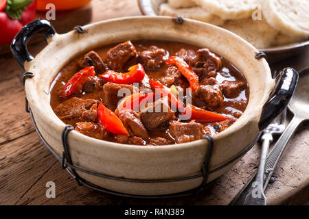 Eine Schüssel mit köstlichen authentisch Ungarisches Gulasch mit Semmelknödel und rote Paprika garnieren. Stockfoto