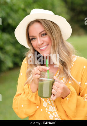 Lächelnde junge Frau mit Smoothie in Mason jar Stockfoto