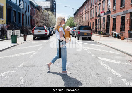 Die Mutter ihre Tochter in Baby carrier Stockfoto