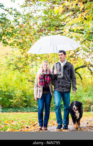 Frau und Mann in Spaziergang mit Hund im Herbst regen Stockfoto