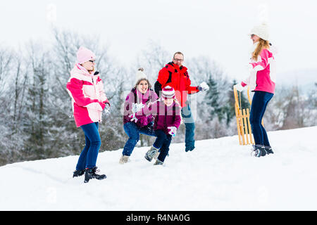 Familie mit Kindern in Schneeballschlacht im Winter Stockfoto