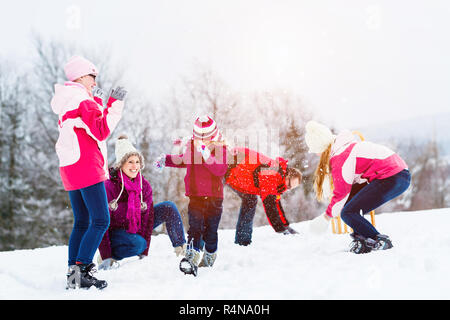 Familie mit Kindern in Schneeballschlacht im Winter Stockfoto