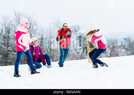 Familie mit Kindern in Schneeballschlacht im Winter Stockfoto