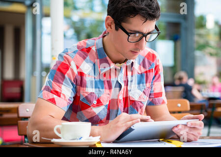 Man trinkt Kaffee in Street Cafe Lesung am tablet device Stockfoto