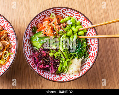 Poke Gericht mit Lachs. Draufsicht auf hölzernen Tisch. Stockfoto