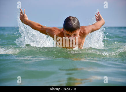 Schwimmer in das offene Meer direkt auf der Kamera Hälfte sichtbar aus dem Wasser die Sonne scheint Stockfoto