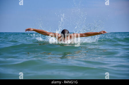 Schwimmer in das offene Meer direkt auf der Kamera Hälfte sichtbar aus dem Wasser die Sonne scheint Stockfoto