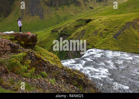 Touristen visitÂ Skogafoss, einem der kultigsten Wasserfälle in Island. Autobahnnähe eigenen (auch als Ring Road bekannt), den Wasserfall Kaskaden 60 Meter und hat Wanderwege, die Besuchern erlauben bis zu Recht auf die unteren und oberen von den Wasserfällen entfernt. Der Wasserfall ist auf der Skoga Fluss, der durch das Hochland von Island reisen, bevor er den Atlantik erreicht. entfernt Stockfoto