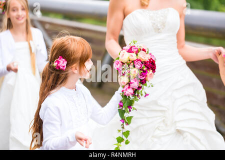 Braut im Brautkleid mit brautjungfern auf Brücke Stockfoto