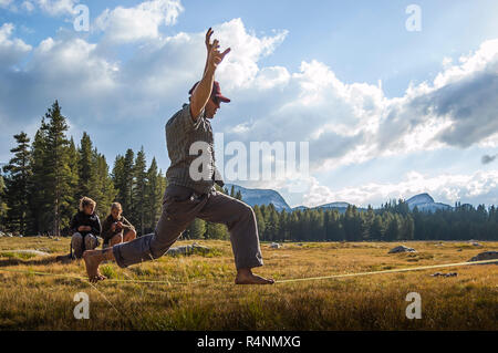 Seitenansicht von abenteuerlichen Mann balancing TuolumneÂ whileÂ slacklining, Wiesen, Yosemite National Park, Kalifornien, USA Stockfoto