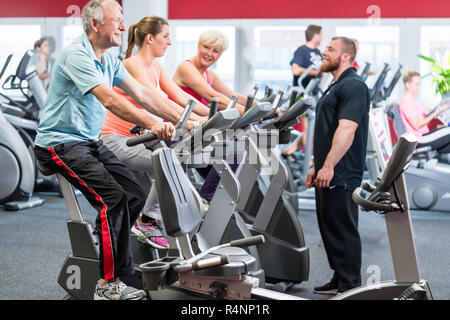 Gruppe spinning mit persönlichem Trainer im Fitnessraum Stockfoto