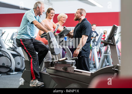 Gruppe spinning mit persönlichem Trainer im Fitnessraum Stockfoto