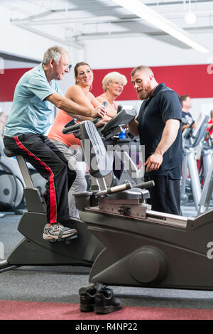 Gruppe spinning mit persönlichem Trainer im Fitnessraum Stockfoto