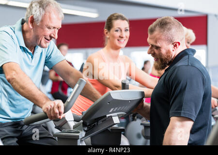 Gruppe spinning mit persönlichem Trainer im Fitnessraum Stockfoto