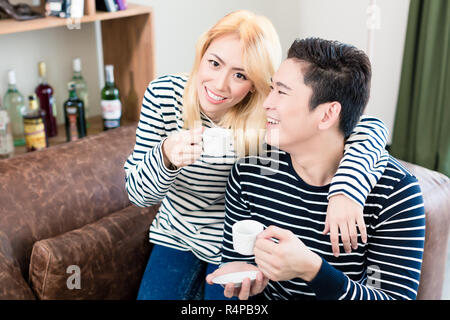 Asiatische Paar auf dem Sofa trinken Kaffee zusammen Stockfoto