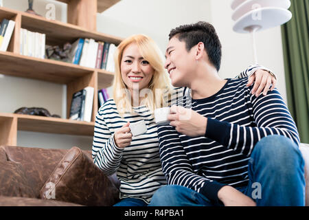 Asiatische Paar auf dem Sofa trinken Kaffee zusammen Stockfoto