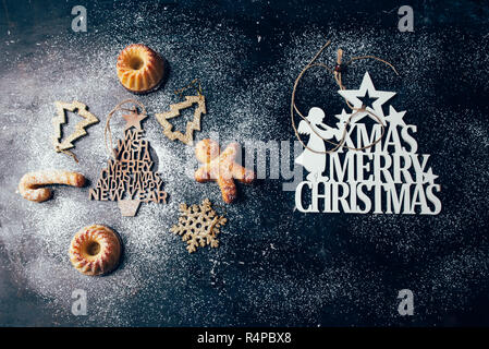 Weihnachten mini bundt Cake und Dekoration auf einem schwarzen Brett mit Puderzucker und Stenciled Weihnachtsgrüße, Ansicht von oben, flach Stockfoto