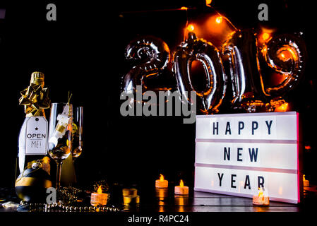 Silvester Feier konzeptionelle Foto, mit Weihnachten Dekoration in goldenen Ton, eine Flasche Champagner, eine Lightbox mit Grüße Text, und in Th Stockfoto