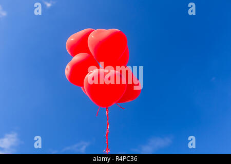 Rote herzförmige Helium Ballone in den Himmel Stockfoto
