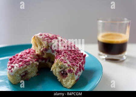 Köstlichen glasierten Krapfen mit Erdbeeren füllen halbieren und eine Tasse schwarzen Kaffee Stockfoto