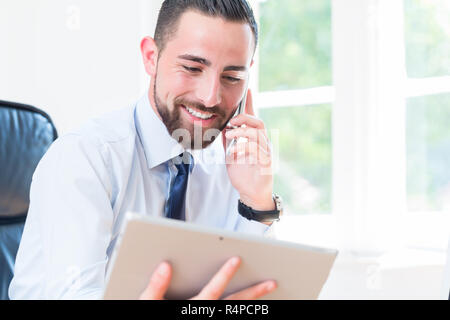 Unternehmer im Büro mit Tablet und Handy Stockfoto