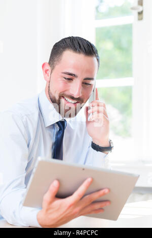 Unternehmer im Büro mit Tablet und Handy Stockfoto