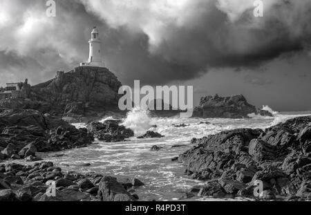 La Corbière Lighthouse, Jersey. Der Leuchtturm befindet sich auf einem Felsen, die eine Flutwelle Insel. Einen Damm links den Leuchtturm bei Ebbe an der Küste. Stockfoto