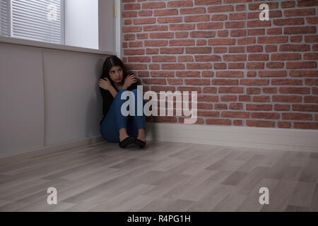 Fürchtete Frau sitzt an der Ecke Stockfoto