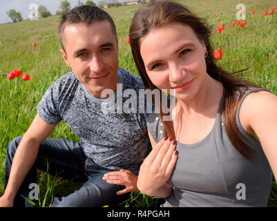 Ein Mädchen und ein Mann sitzen im Freien. Junges Paar in einem Feld der Tulpen. Beziehungen von jungen Menschen Stockfoto