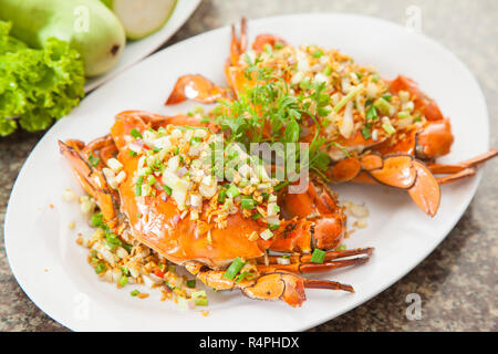 Gebratene rote Krabben mit Zwiebeln, Salat und Kräuter auf weiße Schale Stockfoto