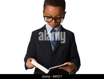 Elegante kleine african-american Boy mit Brille in Business Suit halten das Buch. Studio gedreht. Junge posieren. Stockfoto