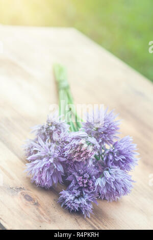 Blume-Schnittlauch gebunden in ein Snop auf ein natürliches Holz Schneidebrett Stockfoto