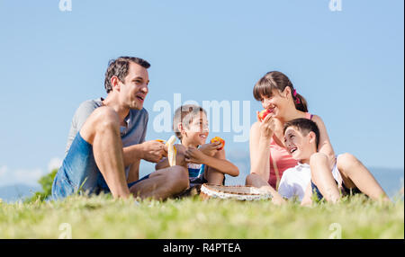 Familie mit zwei Kindern bei einem Picknick mit Früchten im Park im Sommer Stockfoto