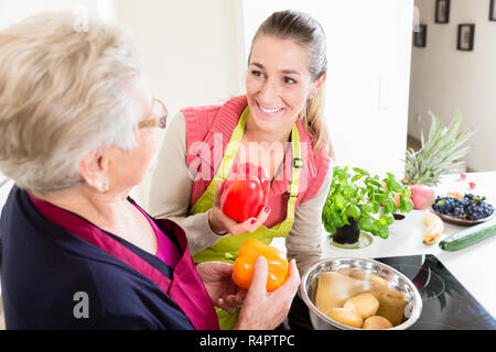 Schwiegermutter erklärt korrekte Verwendung von Paprika in der Küche zu ihrer Schwiegertochter wieder Stockfoto