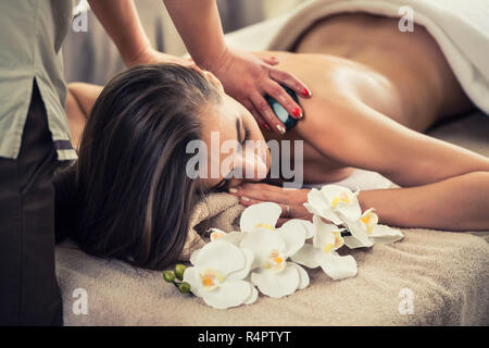 Frau genießen die therapeutischen Effekte von einem traditionellen Hot Stone Massage Stockfoto