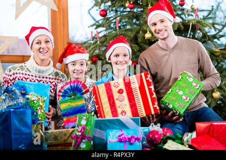 Mama, Papa und Söhne auf X-mas bei der Übergabe der Geschenke unter dem Weihnachtsbaum Stockfoto