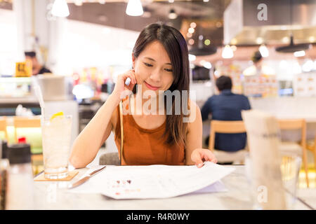 Frau Wahl auf Menü im Restaurant Stockfoto