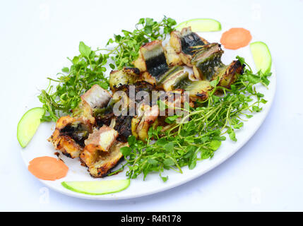 Welsfilet mit Gurken, Karotten und Kräutern auf weißem Teller Stockfoto