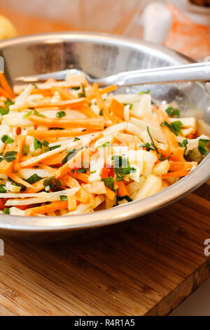 Kohlrabi-Karotten-Salat mit Apfel-Ingwer-Sauce auf Holzbrett Stockfoto