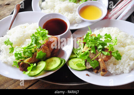 Vietnamesische gebrochen Reis oder com Tam mit gebratene Hähnchenschenkel, Schweinefleisch und Kräutern Stockfoto