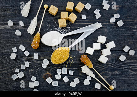 Zucker weiß und braun in Löffel, Crystal und Würfel auf dem Hintergrund eines schwarzen Brett von oben granulierten Stockfoto