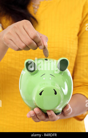 Weibliche Hände halten ein Sparschwein Stockfoto