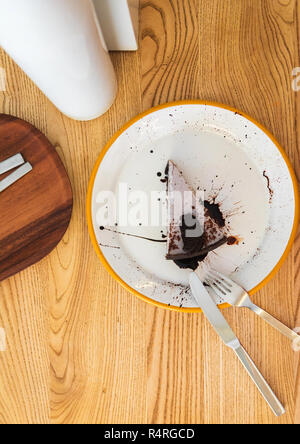 Ein Stück cremige Käsekuchen mit Chocolate Chip Cookies und Schokolade Topping auf einem weißen Teller mit Messer und Gabel. Ansicht von oben Stockfoto