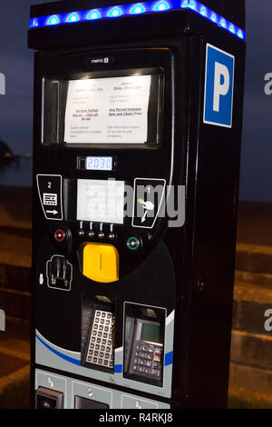 Moderne Parkuhr und Zeichen zeigen, Beschränkungen in Walisisch und Englisch sprachen. Küste von North Wales Llandudno Großbritannien in der Nacht. Stockfoto