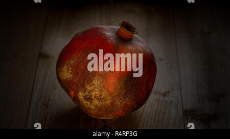 Eine ganze (ganzen) Granatapfel Obst gegen Holz Hintergrund - still life Konzept Stockfoto