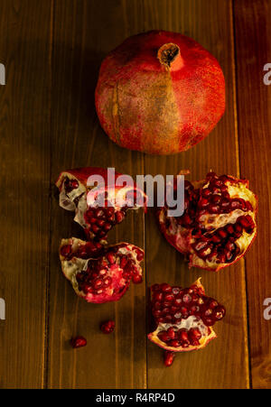 Zwei Granatapfel Obst, eine ganze und eine offene, gegen Holz- Tabelle, Ansicht von oben - gesunde ernährung Konzept Stockfoto