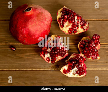 Zwei Granatapfel Obst, eine ganze und eine offene, gegen Holz- Tabelle, Ansicht von oben - gesunde ernährung Konzept Stockfoto