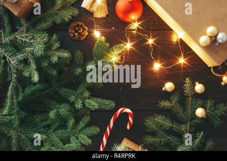 Handgefertigte Weihnachten Geschenkboxen und Weihnachtslichter auf dunklem Hintergrund, oben flach Stockfoto