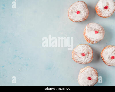 Hanukkah food Krapfen mit Marmelade und Zucker Pulver auf blauem Hintergrund. Jüdische Feiertag Hanukkah Konzept und Hintergrund. Kopieren Sie Platz für Text. Top View oder flach. Stockfoto