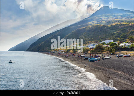 Stromboli, Äolische Inseln, Italien - 9. September 2017: Personen mit schwarzen vulkanischen Strand mit Stromboli Vulkan im Hintergrund entspannen Stockfoto